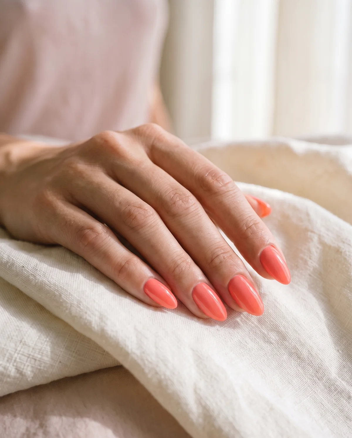 A hand with coral gel nails